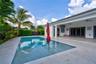 Outdoor patio featuring a covered lanai with ceiling fans, an integrated rectangular swimming pool, and stone-finish paving