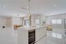 Kitchen featuring a central island with a stone-finish countertop and integrated beverage refrigerator, large-format tile flooring, recessed ceiling l
