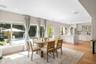Open-concept kitchen and dining area featuring wood-finish flooring, recessed lighting, built-in ceiling speakers, and white cabinetry with a central 
