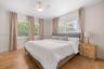 Wood-finish flooring, neutral wall tones, multi-pane sliding windows, and a ceiling fan with integrated light fixture