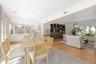 Open-concept kitchen and dining area featuring white shaker-style cabinetry, wood-finish flooring, custom built-in arched shelving, and recessed light