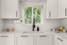 White shaker-style cabinetry with matte black hardware, stone-patterned countertops, integrated white apron-front sink, matte black gooseneck faucet, 
