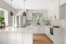 Kitchen featuring white cabinetry with matte black hardware, stone countertops with matching backsplash, wood-finish flooring, stainless steel built-i