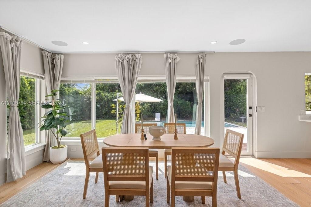 Expansive picture windows, light wood-finish flooring, arched doorway, and built-in ceiling speakers