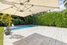 Outdoor living area featuring a light-toned stone patio, a rectangular swimming pool with a built-in step, and perimeter landscaping consisting of mat