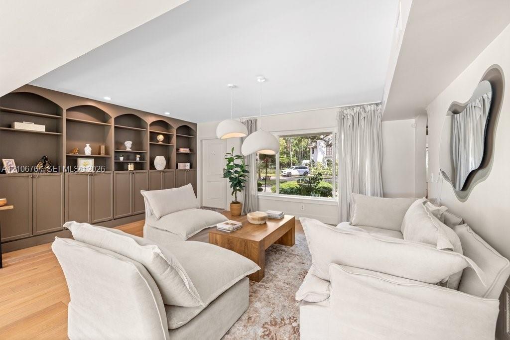 Custom floor-to-ceiling built-in cabinetry, wood-finish flooring, recessed lighting, and large picture window