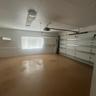 Garage space featuring an epoxy-coated floor, horizontal window with blinds, overhead light fixtures, and wall-mounted cabinetry