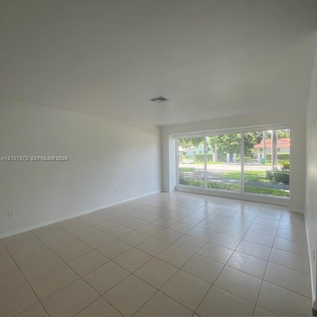 Interior space featuring neutral wall tones, large-format ceramic tile flooring, and a expansive floor-to-ceiling multi-pane window
