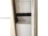 Stacked laundry center featuring a white top-load washer and front-load dryer enclosed by louvered bi-fold doors