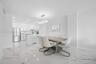 Polished stone-finish flooring, kitchen island with built-in cabinetry, stainless steel refrigerator, and modern oval-shaped pendant lighting