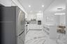 Kitchen featuring white high-gloss cabinetry, stainless steel appliances, built-in island with open shelving, recessed lighting, and large-format tile