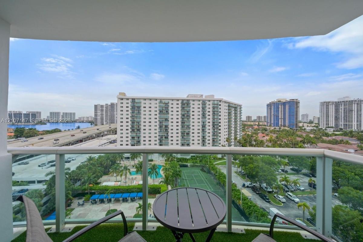 Private balcony featuring a glass-panel railing and synthetic turf flooring
