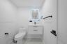 Floating vanity with integrated sink, matte black hardware, backlit rectangular mirror, and stone-finish flooring