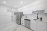 Kitchen featuring white high-gloss cabinetry, stainless steel appliances, solid-surface countertops, a matte black pull-down faucet, and polished ston