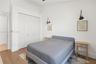 Room featuring wood-finish flooring, white bi-fold closet doors, and dual black wall-mounted swing-arm sconces