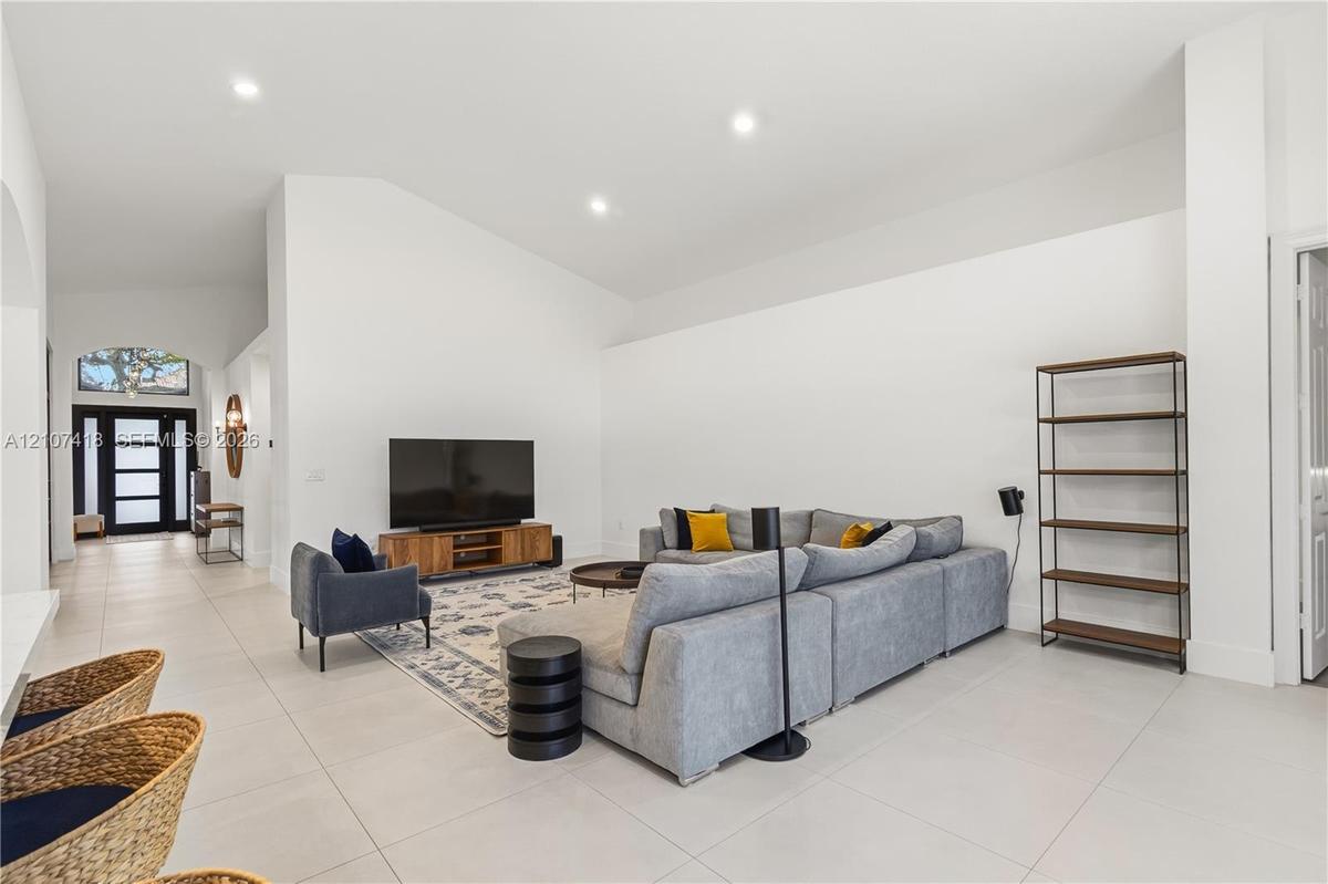 Vaulted ceilings, neutral ceramic tile flooring, recessed lighting, and a multi-pane glass entry door