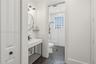 Bathroom featuring a console-style vanity with a rectangular sink, matte black plumbing fixtures, white subway tile wall treatments, and hexagonal flo