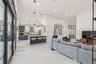 Open-concept kitchen featuring two-toned cabinetry, a large central island, recessed lighting, glass-paneled interior partitions, and porcelain tile f