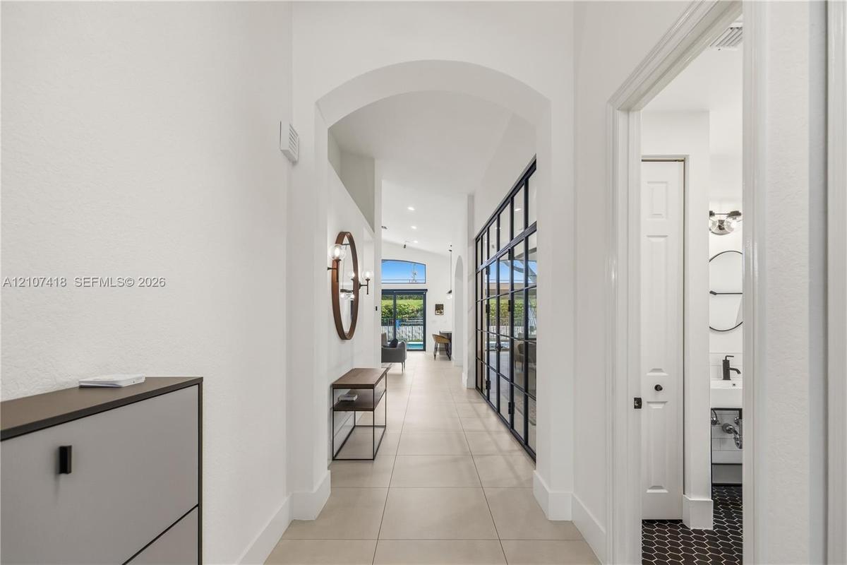 Entryway featuring a high arched passage, large-format tile flooring, recessed ceiling lighting, and a floor-to-ceiling metal-framed glass partition