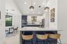 Kitchen featuring a central island with a solid surface countertop, contrasting navy and white cabinetry, a built-in double wall oven, patterned tile 