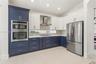 Kitchen featuring two-tone cabinetry, stainless steel double wall oven, stainless steel refrigerator, patterned mosaic tile backsplash, and quartz cou