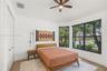 Room featuring wood-finish flooring, a ceiling fan with integrated lighting, and large windows with dark-finish frames