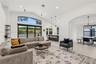 Vaulted ceilings, expansive windows with exterior transom, large-format tile flooring, recessed lighting, and kitchen island with pendant fixtures