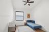 Room featuring wood-finish flooring, a matte black multi-blade ceiling fan with integrated lighting, and a window with a matte black frame