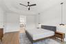 Tray ceiling, wood-finish flooring, matte black ceiling fan, and dual suspended pendant light fixtures
