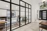 Floor-to-ceiling iron-frame glass room divider, recessed lighting, tile flooring, arched entryway, and front door with glass inserts