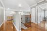 Wood-finish flooring, decorative wrought iron balusters with a wooden handrail, crown molding, and multi-panel interior doors