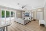 Living area featuring wood-finish flooring, crown molding, recessed lighting, built-in floor-to-ceiling shelving, and multi-panel glass patio doors