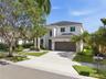 Two-story stucco exterior featuring a concrete tile roof, attached two-car garage, and mature professional landscaping