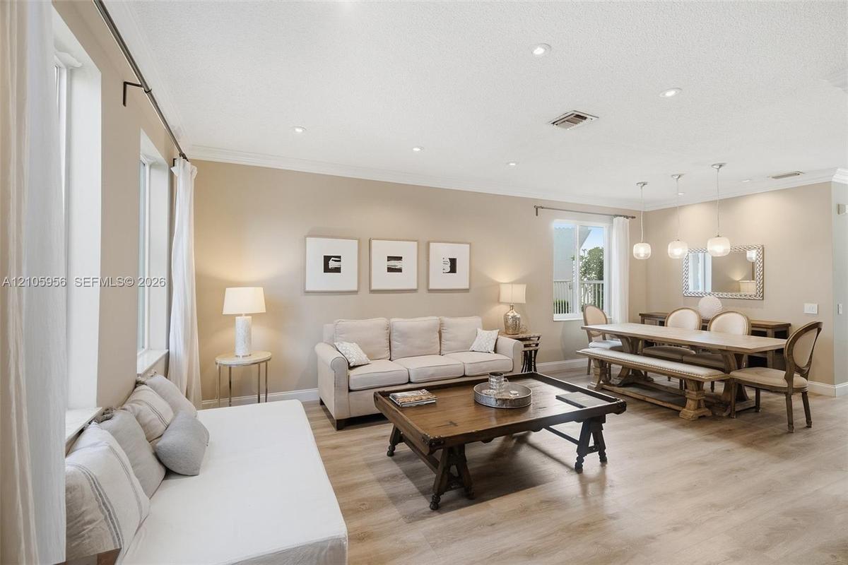 Open-concept interior featuring wood-finish flooring, recessed lighting, crown molding, and pendant lighting over the dining area