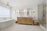 Freestanding soaking tub, double-sink vanity with stone countertop, brass-finished hardware, and glass-enclosed walk-in shower