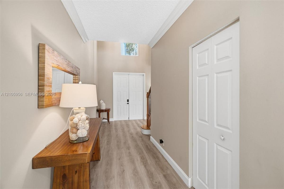 Entryway featuring double-door entry, vaulted ceilings, high-placed window, wood-finish flooring, and a multi-panel bi-fold closet door