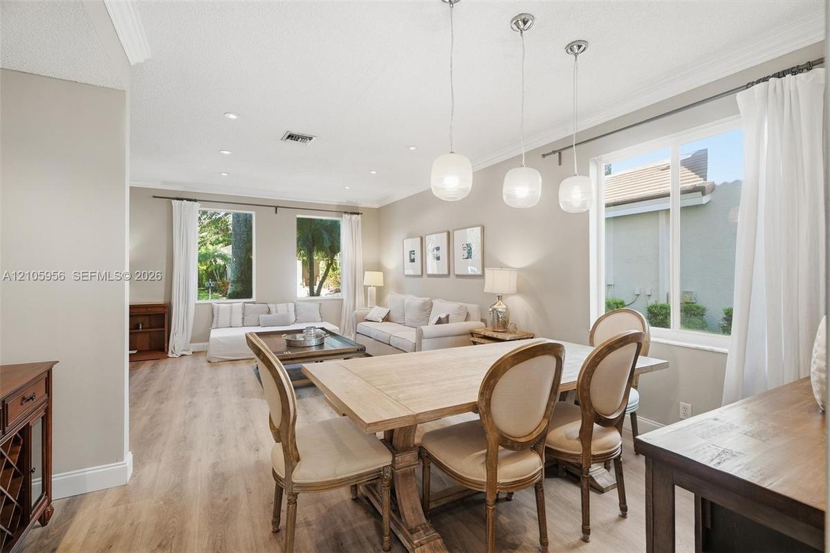 Neutral interior space featuring wood-finish flooring, recessed lighting, crown molding, and glass globe pendant lighting