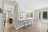 Kitchen featuring white shaker-style cabinetry, quartz countertops with a breakfast bar, stainless steel undermount sink, wood-finish flooring, and re
