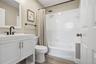 Bathroom featuring a white vanity cabinet with a rectangular undermount sink, matte black faucet hardware, wood-finish flooring, and a tiled shower-tu