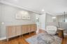 Interior space featuring wood-finish flooring, crown molding, a built-in multi-door cabinetry unit, and a wall-mounted picture light