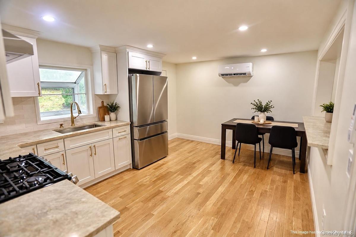 Kitchen featuring white shaker-style cabinetry, stainless steel appliances, recessed lighting, and wood-finish flooring