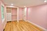 Interior space featuring wood-finish flooring, built-in closet organization with integrated drawer storage, a two-panel interior door with matte black