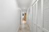 Hallway featuring recessed ceiling lighting, tile flooring, and custom louvered closet doors with polished hardware