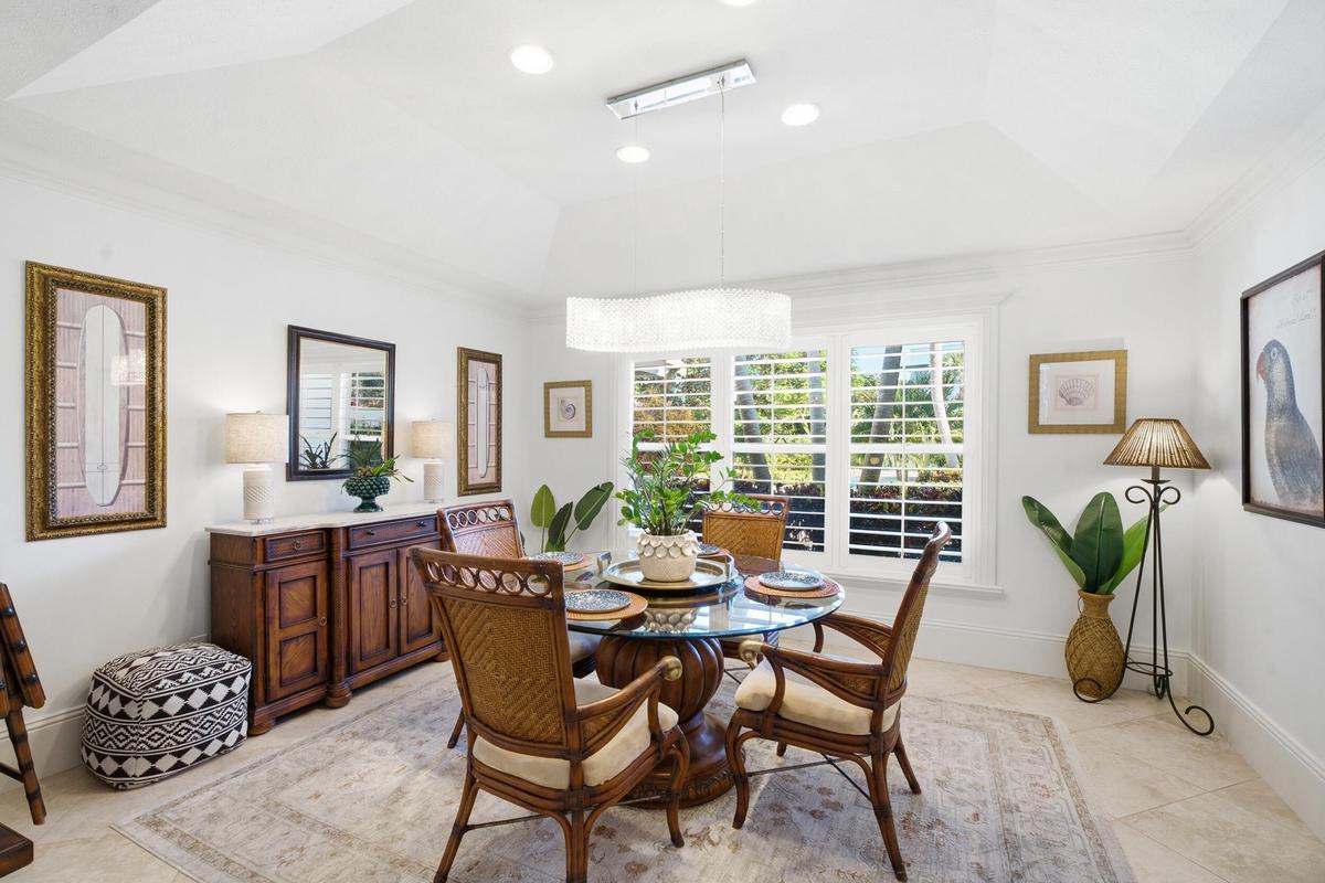 Tray ceiling with recessed lighting, tile flooring, plantation shutters, and a suspended contemporary chandelier