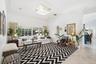 High-ceiling interior featuring crown molding, large-format tile flooring, oversized sliding glass doors, and a decorative crystal flush-mount light f