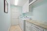 Laundry area featuring tile flooring, built-in white cabinetry, stone-finish countertops, and an integrated hanging rod