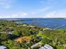 Aerial perspective showcasing a coastal residential neighborhood featuring mature canopy trees, paved roadways, and extensive waterfront access with m