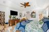 Tray ceiling with recessed lighting and multi-blade ceiling fan featuring organic-inspired design, stone tile flooring, and shutter window coverings