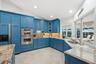Kitchen featuring blue cabinetry, stone countertops, stainless steel double wall oven, tile flooring, and windows with recessed lighting