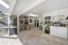 Screened outdoor living area featuring stone-tile flooring, a vaulted ceiling with a skylight, recessed lighting, and built-in cabinetry with stone co